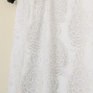 May include: White curtain panel with a grey paisley pattern. The curtain is hung on a black curtain rod.