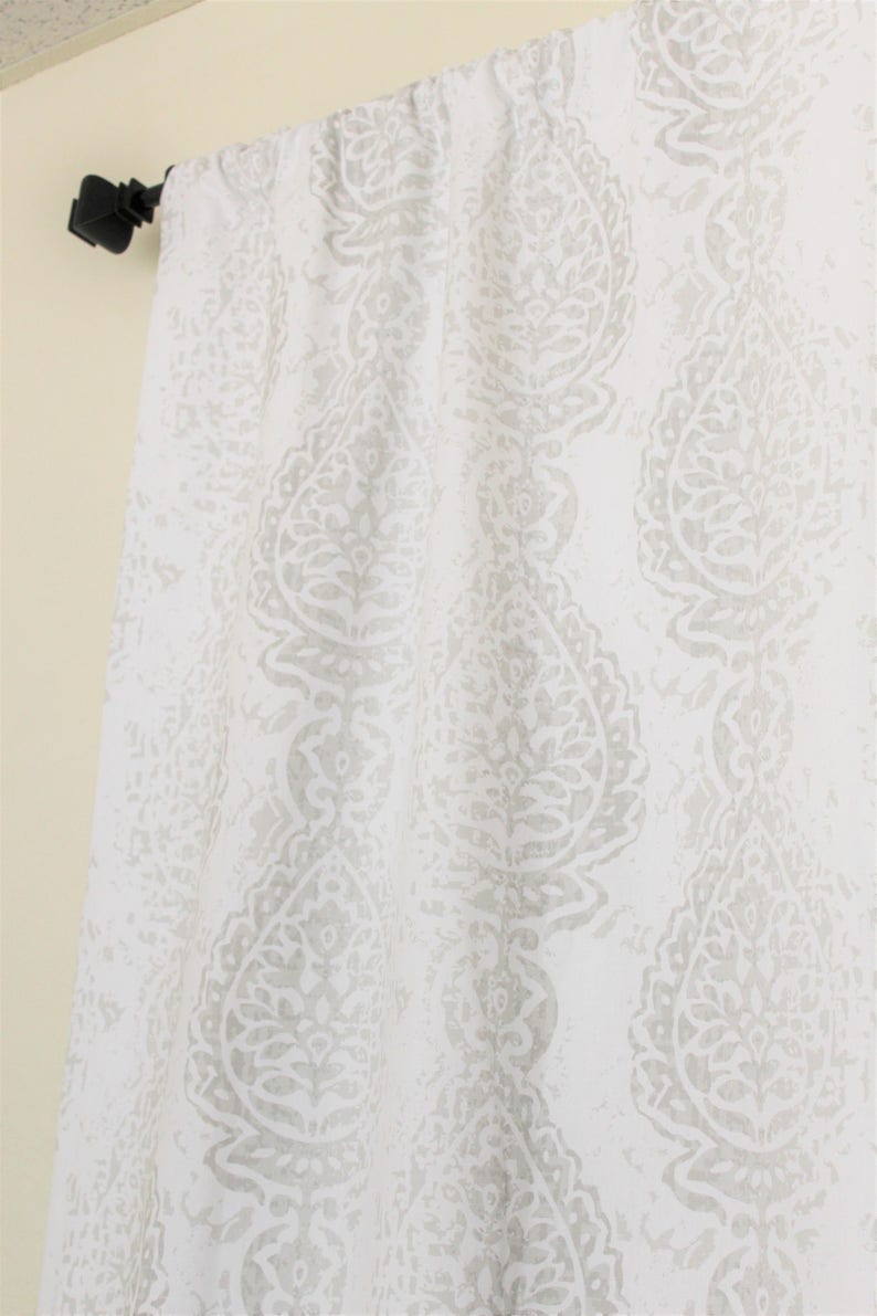 May include: White curtain panel with a grey paisley pattern. The curtain is hung on a black curtain rod.