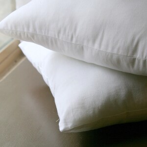 May include: Two white pillowcases stacked on top of each other. The pillowcases are made of a soft, smooth fabric.