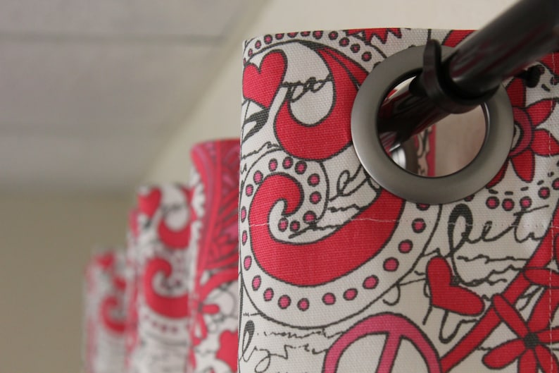 May include: Close-up of a red and white patterned curtain with a silver grommet and a black curtain rod. The curtain has a peace sign and hearts printed on it.