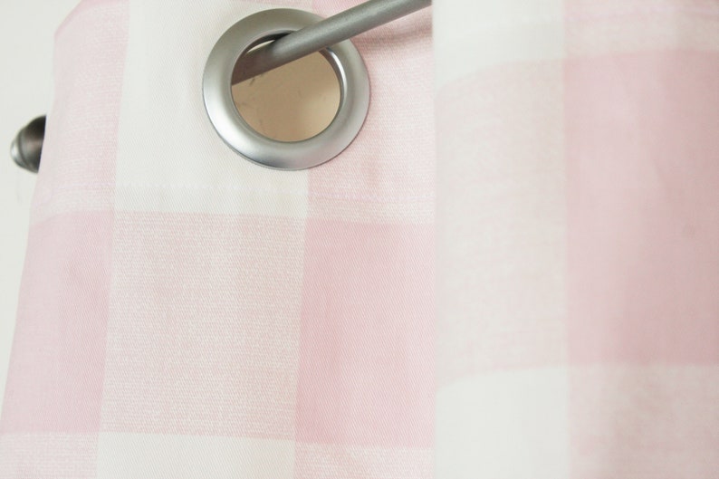 May include: Close-up of a pink and white gingham curtain with a silver eyelet and rod.