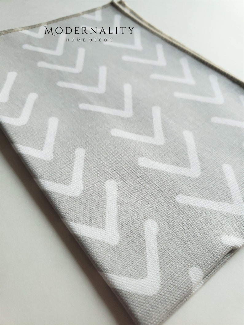 May include: Grey fabric with a white chevron pattern. The fabric has the text "MODERNALITY HOME DECOR" printed on it.