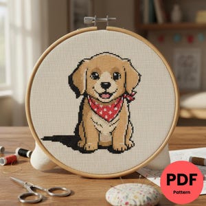 Peut inclure: Un cercle de broderie au point de croix représentant un chiot souriant portant un bandana rouge à pois blancs. Le chiot est brun clair avec des accents noirs. Le cercle est maintenu dans un cadre en bois. Le fond est un tissu beige clair.