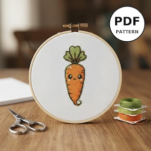 Peut inclure: Un motif de point de croix d'une carotte de dessin animé avec un visage souriant et des feuilles vertes, présenté dans un cercle à broder en bois. Le texte "PDF PATTERN" est dans un cercle blanc. Ciseaux et bobines de fil sont à proximité.