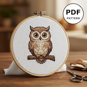 Peut inclure: Un motif de broderie au point de croix représentant un hibou dans un cercle à broder en bois. Le hibou est brun et beige, perché sur une branche marron. Le texte "PDF PATTERN" est dans un cercle noir.