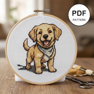 Peut inclure: Un cercle de broderie au point de croix représentant un chiot golden retriever souriant portant un bandana. Le chiot est brodé dans des tons de beige et de marron, sur fond blanc. Le texte "PDF PATTERN" est dans un cercle noir.