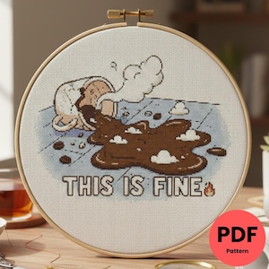 Peut inclure: Broderie au point de croix dans un cercle en bois. L'image représente une tasse de café renversée et une flaque de café, avec le texte "THIS IS FINE". Le motif est brodé sur un tissu clair, avec un thème humoristique.