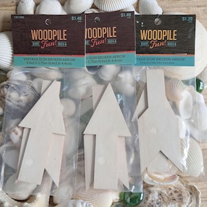 Puede incluir: Tres paquetes de flechas de madera con la inscripción "WOODPILE Fun! 2014" en las etiquetas. Los letreros de color claro miden 9,9 x 3,8-4,4 cm. El fondo está decorado con conchas marinas.