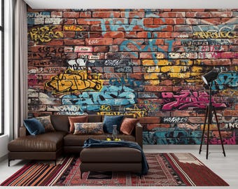May include: A brown leather sectional sofa with a matching ottoman sits in front of a brick wall covered in colorful graffiti art. A black floor lamp stands to the right, and a patterned rug lies on the floor.