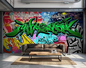 May include: A brown leather sofa and a rectangular wooden coffee table are positioned in front of a large brick wall covered in vibrant, multi-colored graffiti art featuring bold green lettering, abstract shapes, and various stylized tags.