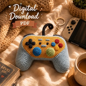 May include: A crocheted video game controller keychain in blue, yellow, black, red, and green. The controller has a black joystick and a gold keychain ring. The image also includes the text "Digital Download PDF".