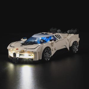 May include: A white toy sports car with a sleek design, illuminated by bright headlights and interior lights. The car features detailed wheels and a blue-tinted windshield. The image is set against a dark background, highlighting the car's features.
