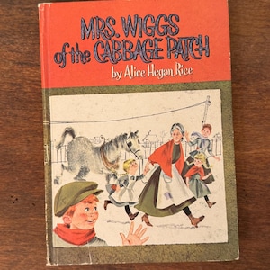 May include: Vintage hardcover book titled "Mrs. Wiggs of the Cabbage Patch" by Alice Hegan Rice. The cover features an illustration of a woman and children running, with a horse and a boy in the foreground. The book has a red top and a green border.