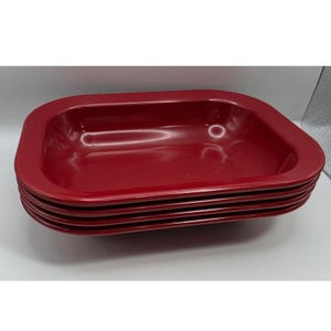May include: A stack of four rectangular, deep-sided baking dishes with rounded corners. Each dish features a smooth, glossy, solid dark red finish with a wide, flat rim extending around the entire perimeter of the vessel.