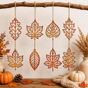 May include: Eight laser-cut wooden leaf ornaments in various shapes, including maple and oak, are suspended in pairs from a horizontal branch by thin twine. Each cutout features intricate vein details and a warm, natural wood finish.