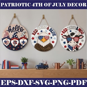 Könnte beinhalten: Patriotische 4. Juli Dekoration mit drei runden Holzschildern. Ein Schild zeigt "hello" mit Zwergfiguren, ein anderes "Red White & Blue" mit einem Adler und das letzte "Red White & Moo" mit einer Kuh. Alle Schilder haben Seilaufhänger.