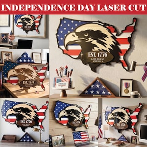Puede incluir: Arte de pared de madera cortado con láser en forma de Estados Unidos, con un diseño de cabeza de águila y el texto "EST. 1776 GOD BLESS AMERICA." La obra utiliza los colores y estrellas de la bandera americana, para el Día de la Independencia.