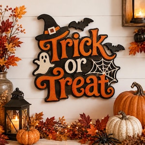 Op de afbeelding: Een decoratief houten wandbord met de tekst Trick or Treat in oranje letters op een zwarte achtergrond. Het bord bevat een zwarte heksenhoed, een wit spookje, een wit spinnenweb en twee zwarte vleermuizen als geïntegreerde elementen.