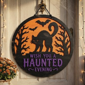 May include: A round wooden door sign featuring a black silhouette of a cat and bats against an orange background. The sign includes bare tree silhouettes and the purple text "WISH YOU A HAUNTED EVENING" hanging from a black rope on a door.