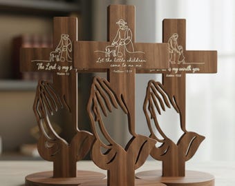 May include: Wooden Christian cross laser cut with praying hands base. The cross features etched illustrations of a shepherd with a lamb and a child, along with Bible verses. The text "CHRISTIAN CROSS LASER CUT" is at the top.