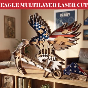 May include: Multilayer laser-cut wooden eagle sculpture with an American flag design. The eagle's wings feature stars and stripes, with silhouettes of soldiers and a map. The text "EAGLE MULTILAYER LASER CUT" is at the top.