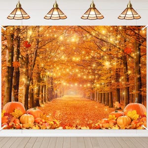 May include: A fall-themed backdrop featuring a pathway through a forest with orange and yellow foliage. Pumpkins and autumn leaves are at the bottom. String lights are strung between the trees, creating a warm, inviting scene.