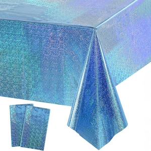 May include: A blue iridescent tablecloth and two matching placemats. The tablecloth is draped over a table, showcasing its shimmering, holographic effect. The placemats are rectangular and share the same color and texture.