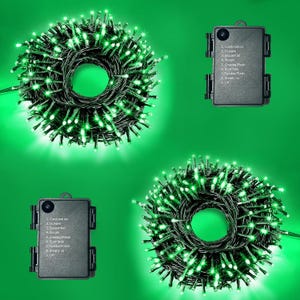 May include: Two coils of green LED string lights with dark green wire and two black battery packs. Each battery pack features a circular button and a printed list of nine lighting modes, including combination, in wave, sequential, and steady on.