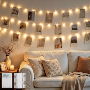 May include: A string of warm white LED fairy lights featuring small clear clips to hold photographs. The lights are arranged in three horizontal rows against a wall, illuminating a series of rectangular prints hanging from the thin wire cord.