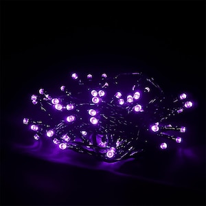 May include: A cluster of small, bright purple LED lights arranged on a dark wire. The individual bulbs are circular and emit a vibrant, glowing violet light against a completely black background, creating a dense, illuminated spherical shape.