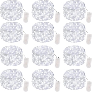 May include: Twelve identical coils of silver wire fairy lights, each featuring small white LED bulbs and a white plastic battery pack. The lights are arranged in a grid pattern, showcasing the thin, flexible wire and the compact power source.