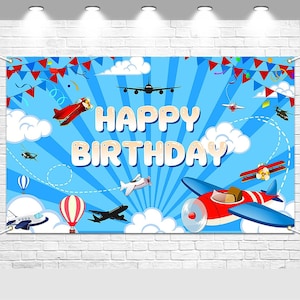 May include: A blue banner with the words "HAPPY BIRTHDAY" in large, white letters. The banner features illustrations of airplanes, hot air balloons, clouds, and confetti against a blue sky background.