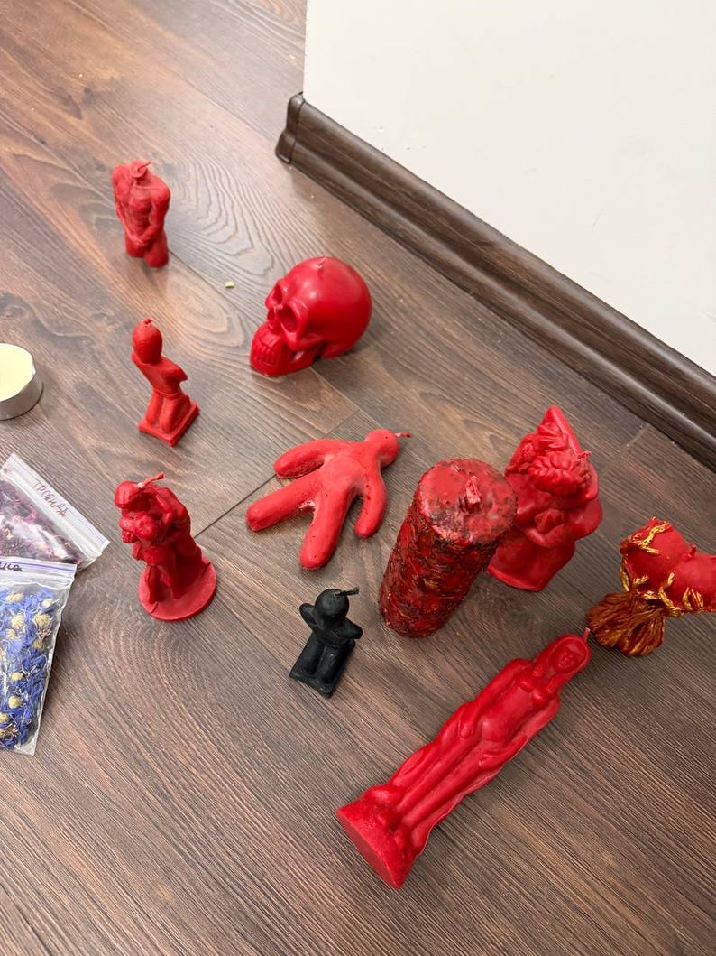 a collection of red and black candles and figurines arranged on a wooden floor.