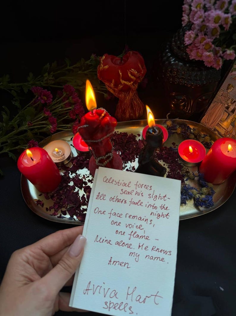 Puede incluir: Un arreglo con velas rojas encendidas, p&eacute;talos secos y una nota manuscrita. La nota dice "Celestial forces...Aviva Hart spells." La escena est&aacute; dispuesta sobre una bandeja plateada con un fondo oscuro.