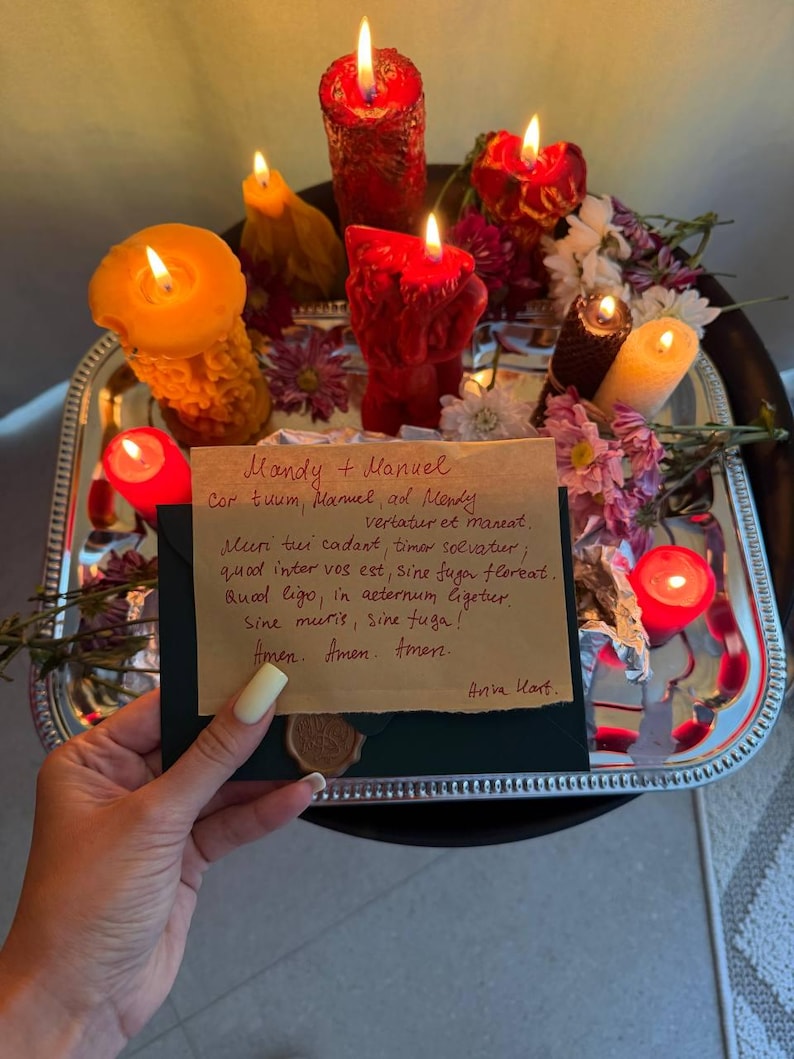 A hand holding a handwritten note with a warm, intimate message, surrounded by a tray of lit candles and flowers, creating a cozy and romantic atmosphere.