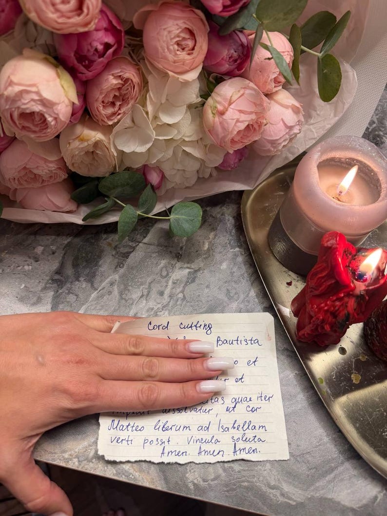 A bouquet of pink and white roses, a candle, and a handwritten note on a gray marble surface.