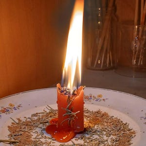 A single lit candle on a plate, with a warm glow and smoke rising from it, creating a cozy and intimate atmosphere.