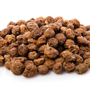 May include: A pile of dried tiger nuts, also known as chufa nuts, against a white background. The nuts are small, round, and have a wrinkled, brown exterior. They are a popular snack and ingredient in various recipes.