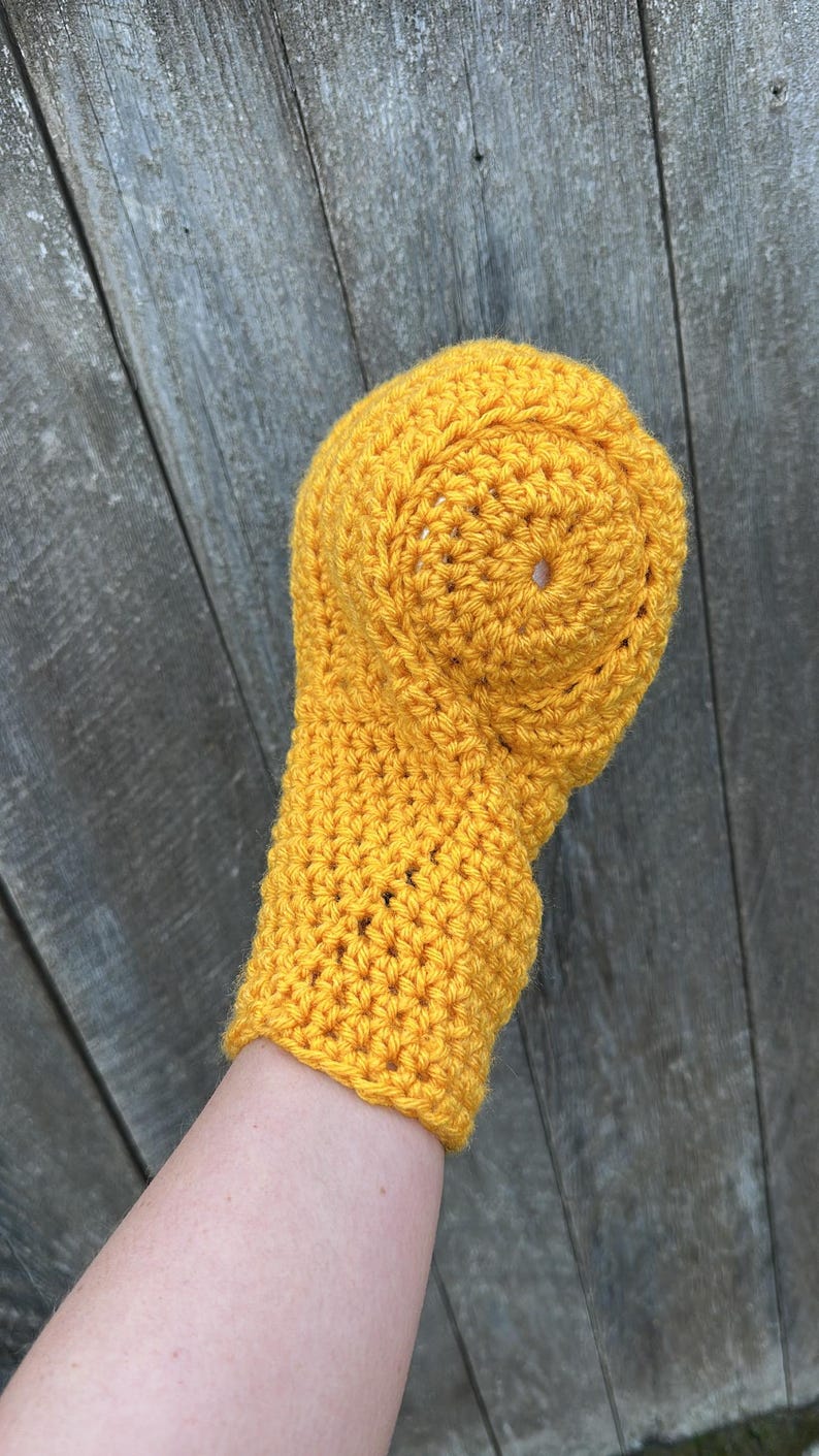 Puede incluir: Un conjunto de gorro y mit&oacute;n de ganchillo amarillo brillante, hecho a mano. El gorro tiene una parte superior redondeada con un peque&ntilde;o agujero, y el mit&oacute;n est&aacute; adjunto. El conjunto est&aacute; hecho de hilo texturizado.