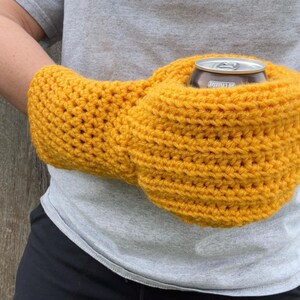 Puede incluir: Un soporte para bebidas de ganchillo amarillo mostaza, dise&ntilde;ado para ser usado alrededor de la cintura. El soporte est&aacute; dise&ntilde;ado para contener una lata de tama&ntilde;o est&aacute;ndar. El art&iacute;culo est&aacute; hecho a mano y parece estar hecho de un hilo suave.