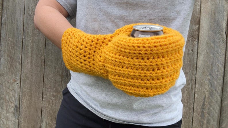 Puede incluir: Un soporte para bebidas de ganchillo amarillo mostaza, dise&ntilde;ado para ser usado alrededor de la cintura. El soporte est&aacute; dise&ntilde;ado para contener una lata de tama&ntilde;o est&aacute;ndar. El art&iacute;culo est&aacute; hecho a mano y parece estar hecho de un hilo suave.