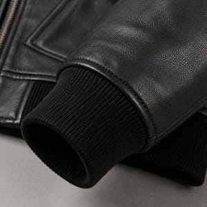 Close-up of ribbed cuff and genuine leather sleeve on black hooded jacket