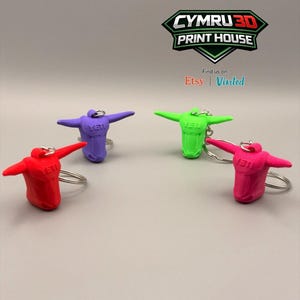 May include: Four bull head keychains in red, purple, neon green, and pink, each featuring the word YETI embossed on the forehead and a silver metal ring. The logo for CYMRU 3D PRINT HOUSE is visible at the top with the text Find us on: Etsy | Vinted.