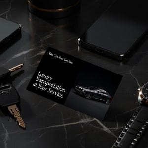 May include: A black and gold wristwatch, two smartphones, a set of keys, and a business card with the text "Luxury Transportation at Your Service" are arranged on a dark, marble-like surface. The business card features a car image.