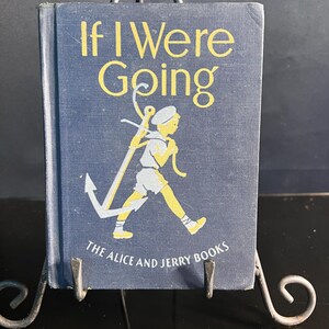 May include: A vintage book titled "If I Were Going" from "The Alice and Jerry Books" series. The cover is navy blue with yellow lettering and a graphic of a boy with an anchor. The book is displayed on a metal stand.