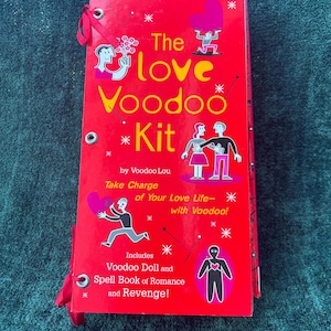 May include: A red "Love Voodoo Kit" with illustrations and text. The kit includes a voodoo doll and a spell book of romance and revenge. The cover features the text "The Love Voodoo Kit" and "Take Charge of Your Love Life - with Voodoo!"