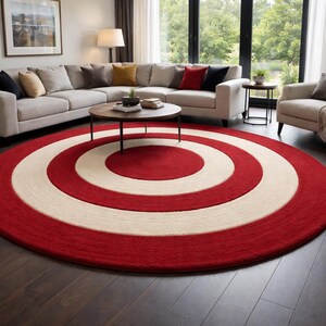 Könnte beinhalten: Ein großer, runder Teppich mit einem Zielscheiben-Design. Der Teppich hat konzentrische Kreise in Rot und Off-White. Er liegt auf einem dunklen Holzboden in einem Wohnzimmer, mit einem Ecksofa und einem Sessel.