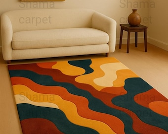 May include: A colorful area rug with a wavy, abstract design in shades of orange, yellow, and teal. The rug is rectangular and placed on a light-colored wooden floor. A cream-colored sofa and artwork are in the background.