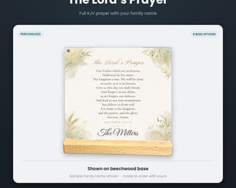 May include: A square plexiglass print featuring The Lord's Prayer in black text with gold accents, decorated with botanical illustrations in the corners. The print is displayed on a light-colored rectangular beechwood base.