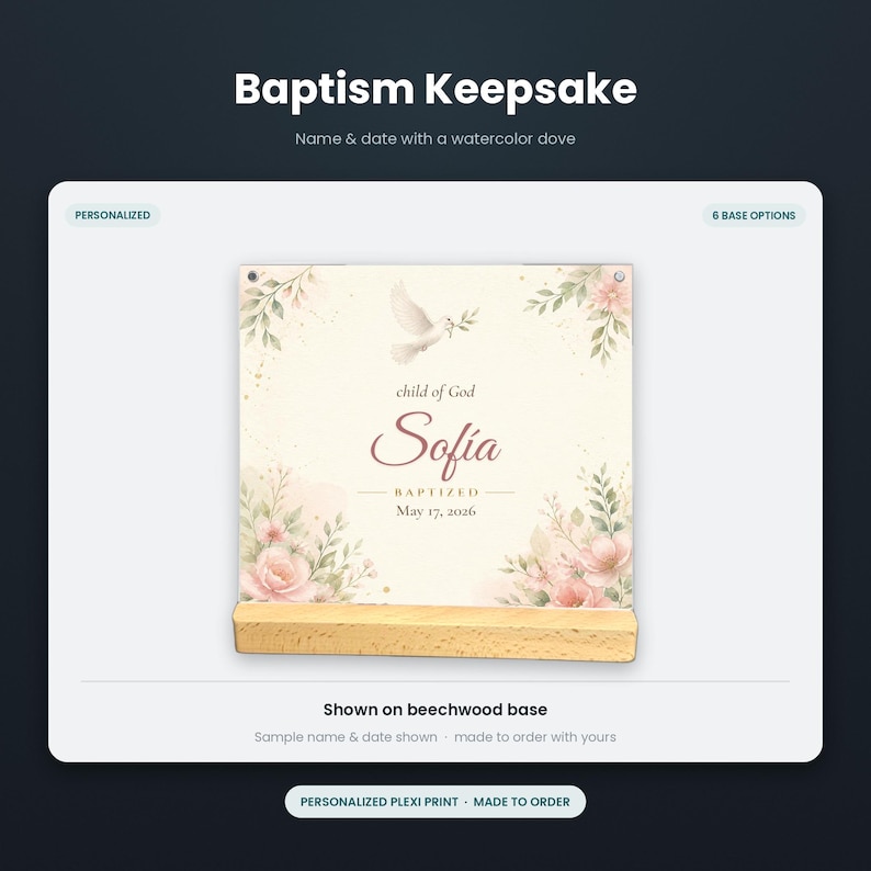 May include: A square plexiglass baptism keepsake print featuring a watercolor dove, pink flowers, and green foliage. The text reads "child of God", "Sofia", "BAPTIZED", and "May 17, 2026". The print is displayed on a rectangular light-colored beechwood base.